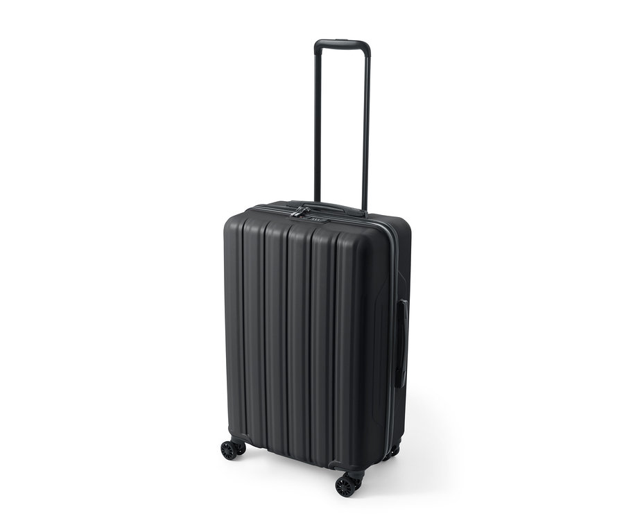 Une valise rigide noire de taille moyenne est posée sur un fond blanc.