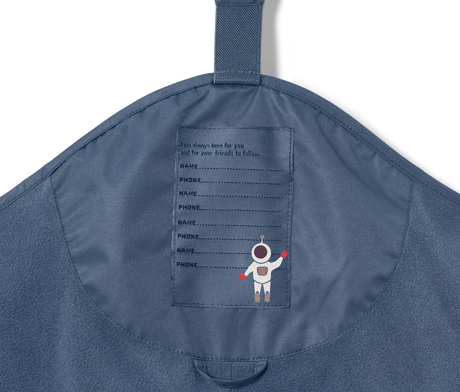 Détail d'un pantalon de pluie thermique pour enfant bleu foncé avec un imprimé astronaute et un espace pour le nom et le numéro de téléphone.