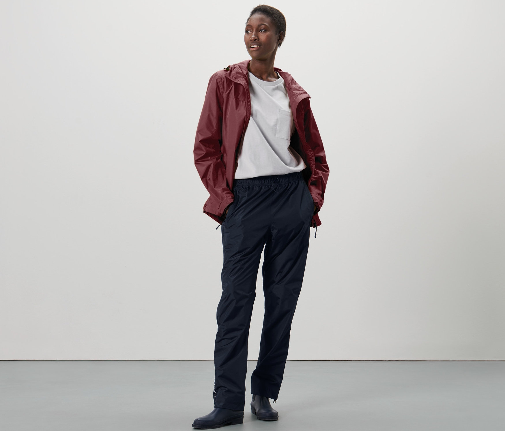 Femme debout portant un pantalon de pluie unisexe high tech.