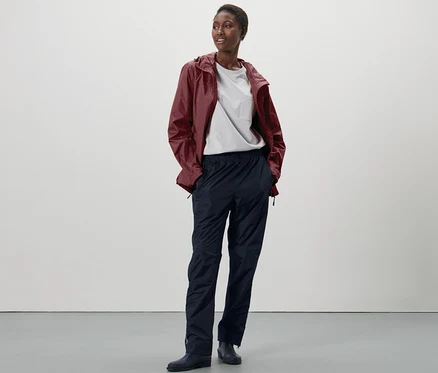 Femme debout portant un pantalon de pluie unisexe high tech.