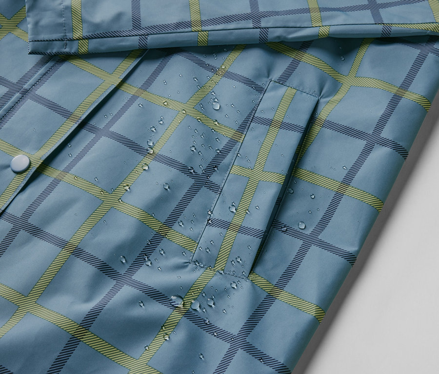 Gros plan sur une veste de pluie bleue à carreaux avec des gouttes d'eau.