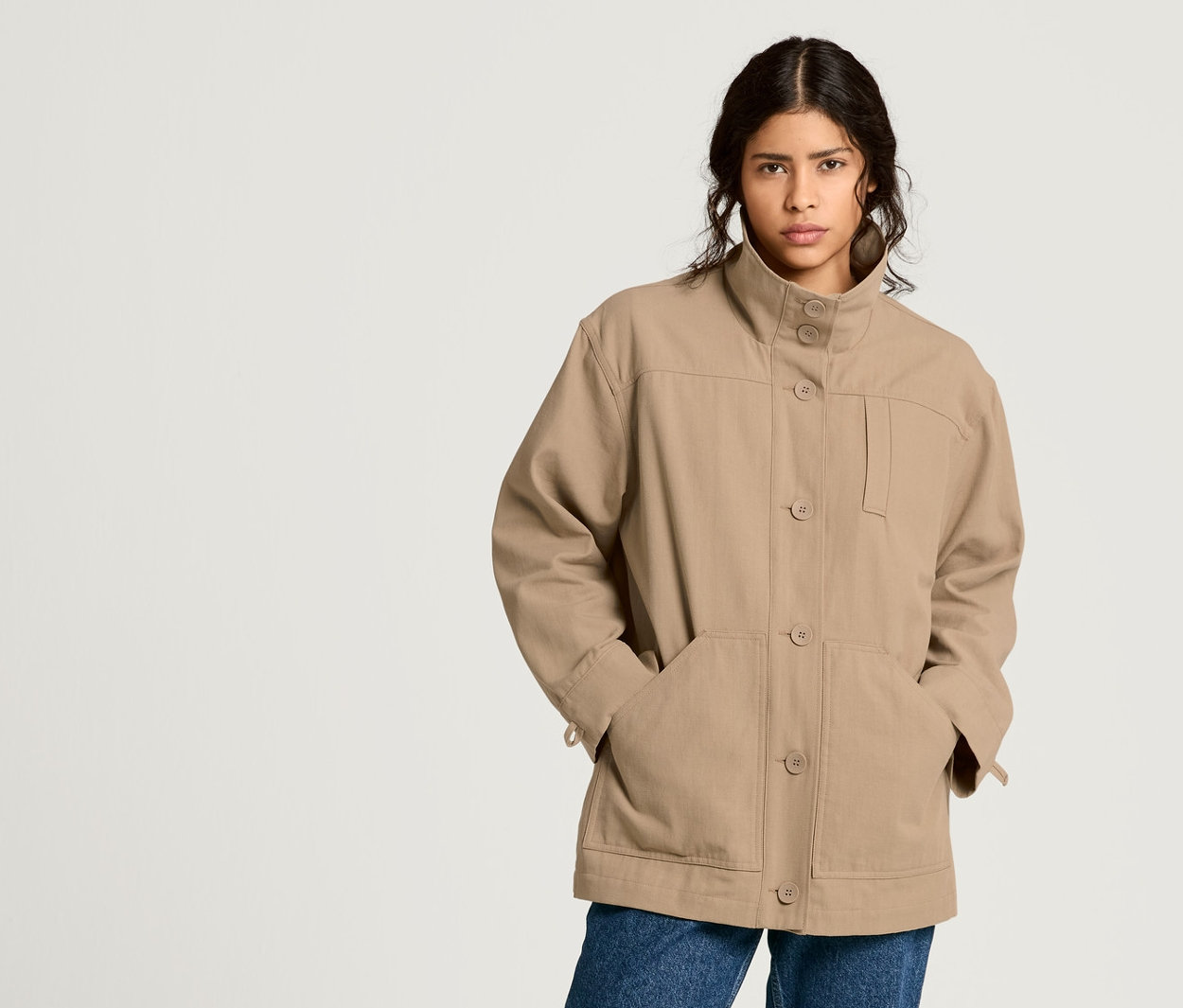 Femme posant en veste NAH/STUDIO en coton recyclé, jean mom et blouse.