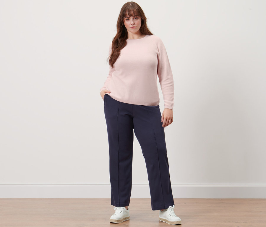 Femme posant en pull en maille et pantalon en jersey avec nervure bleu foncé.