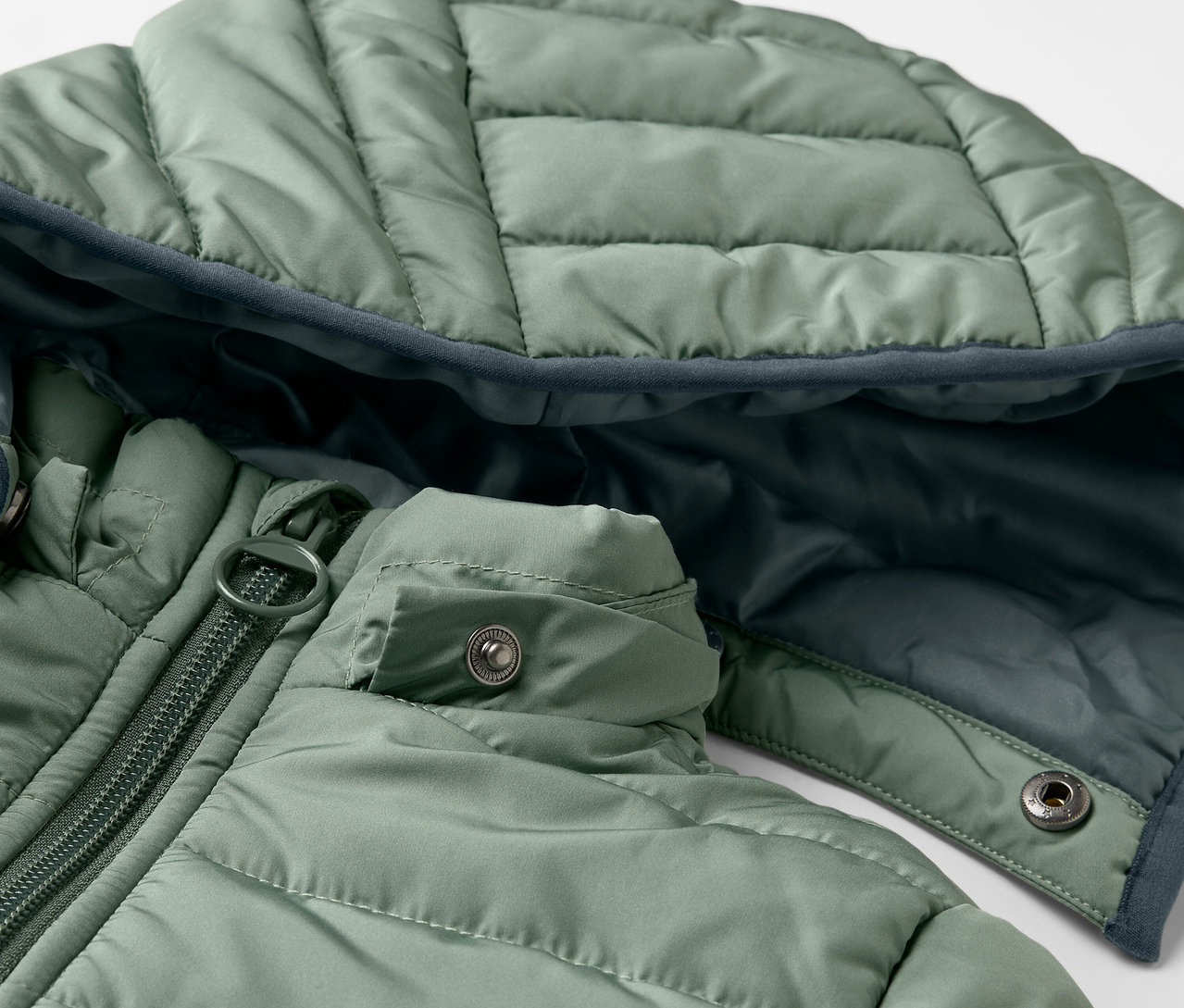 Gros plan sur un anorak matelassé vert pour enfants.