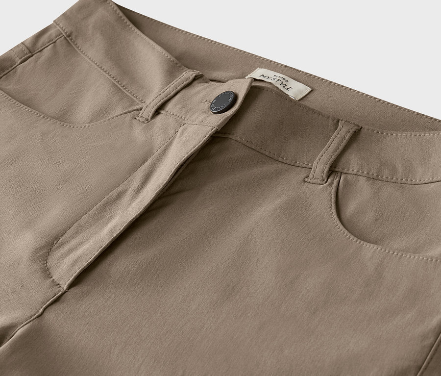 Détail d'un pantalon beige avec bouton.