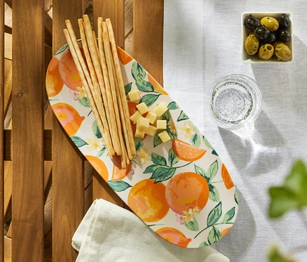 Sur une table en bois se trouvent un saladier de service avec des gressins et du fromage, un verre d'eau et un bol d'olives.
