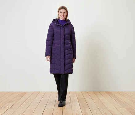 Femme portant un long manteau matelassé violet avec capuche.