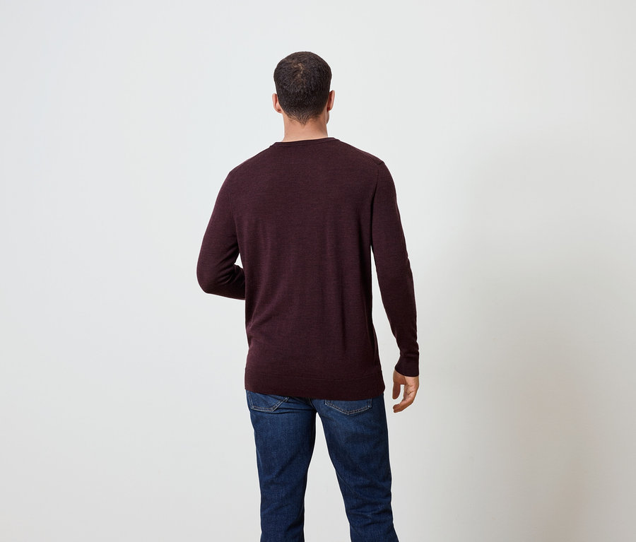 Un homme vu de dos porte un pull bordeaux et un jean.