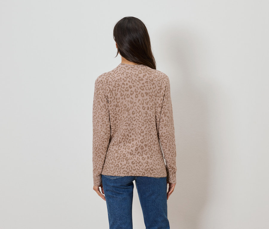 Vue de dos d'une femme aux longs cheveux foncés portant un pull marron clair à motif léopard et un jean bleu.