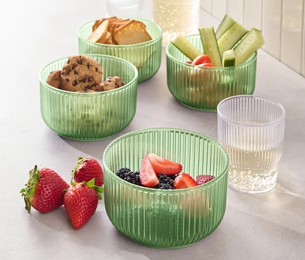 Quatre bols en plastique remplis de nourriture, notamment des biscuits, du pain, des concombres et des fraises.
