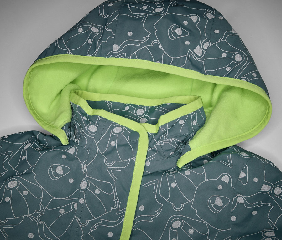 Gros plan sur une veste de pluie thermique pour enfant avec des éléments réfléchissants, une capuche et un motif animalier.