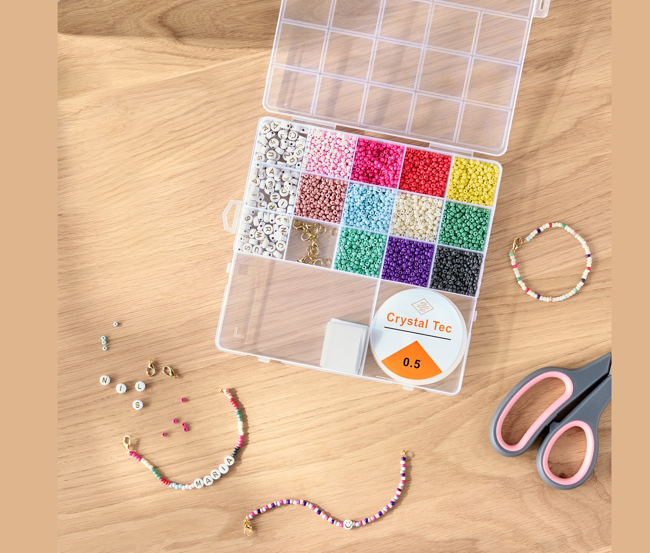 Kit de perles DIY ouvert avec des perles colorées, de la ficelle et des ciseaux sur une table en bois.