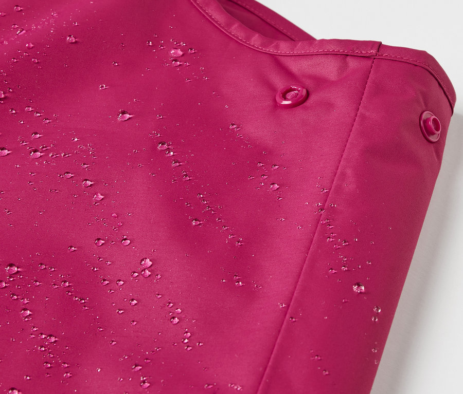 Détail d'un pantalon de pluie thermique pour enfant, baie, avec des gouttes d'eau.