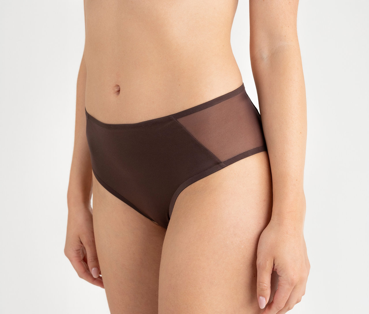 Une personne porte un slip taille haute Passionata « Bianca » couleur chocolat noir avec des empiècements en maille sur les côtés.