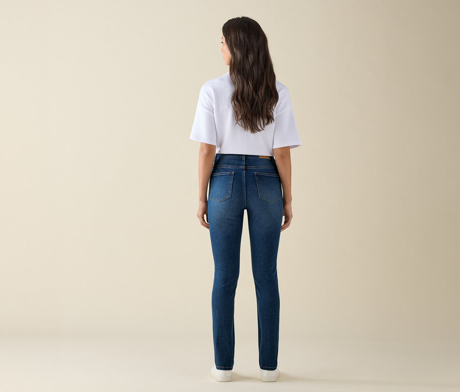 Femme vue de dos portant un jean slim «
Ama
» en denim bleu moyen et un t-shirt blanc.