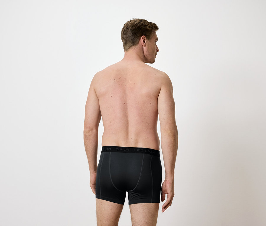 Vue arrière d'un homme portant un boxer noir sur fond blanc.