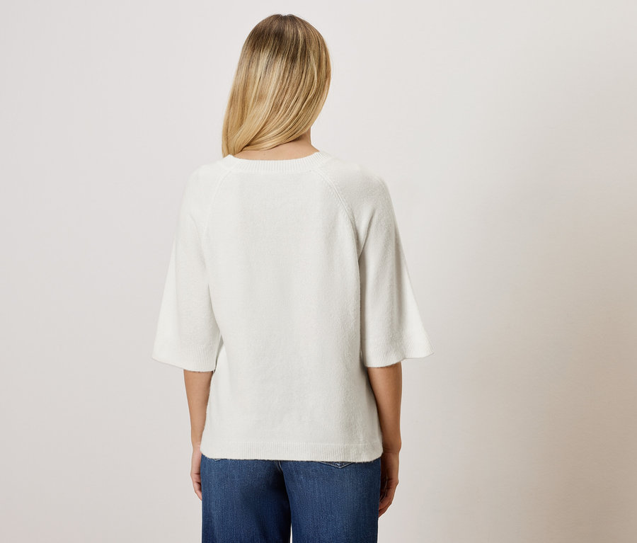 Vue arrière d'une femme aux cheveux blonds portant un chemisier blanc et un jean bleu.