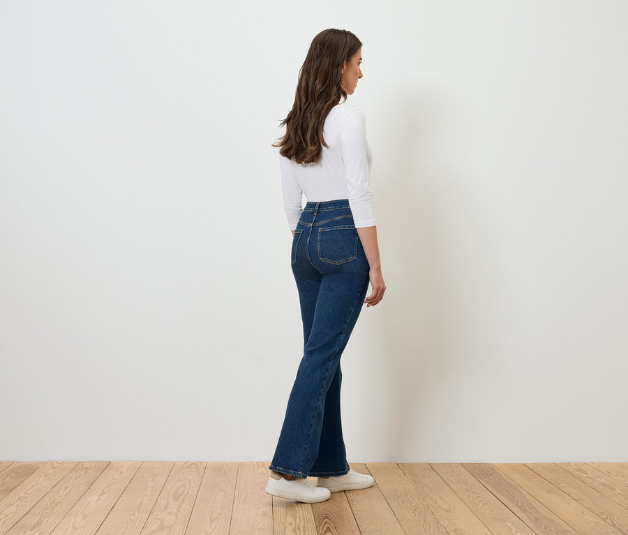 Femme posant en jean et haut blanc.