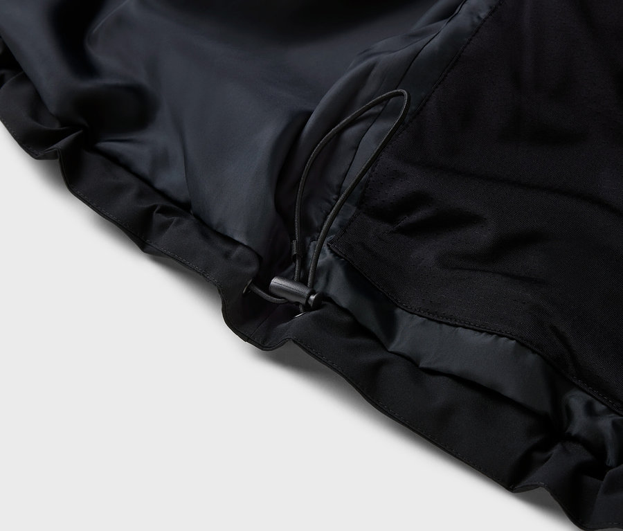 Gros plan sur une veste noire avec cordon de serrage.