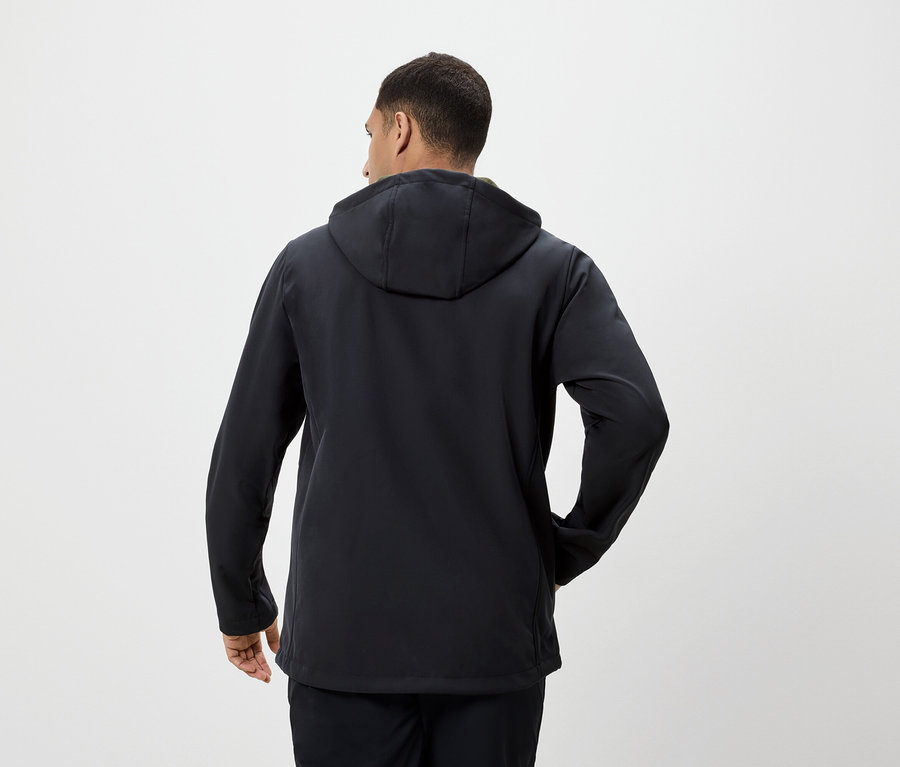 Un homme vu de dos porte une veste à capuche noire.