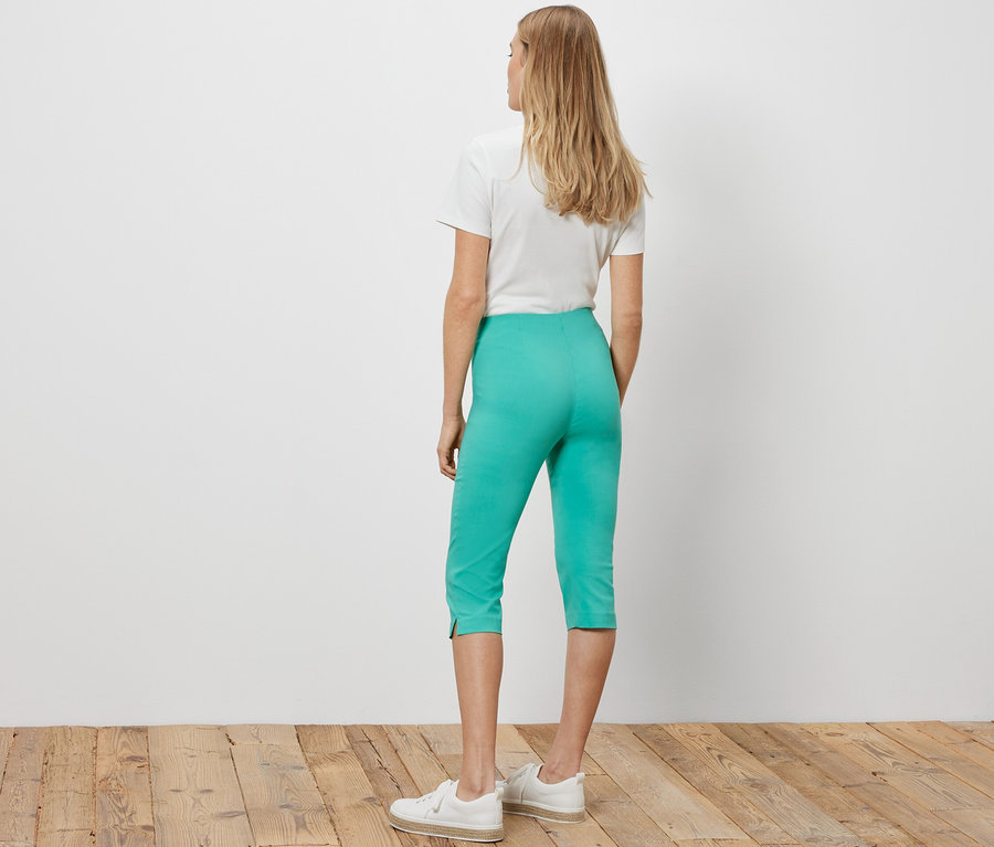 Une femme, vue de dos, porte un pantalon 3/4 stretch turquoise.