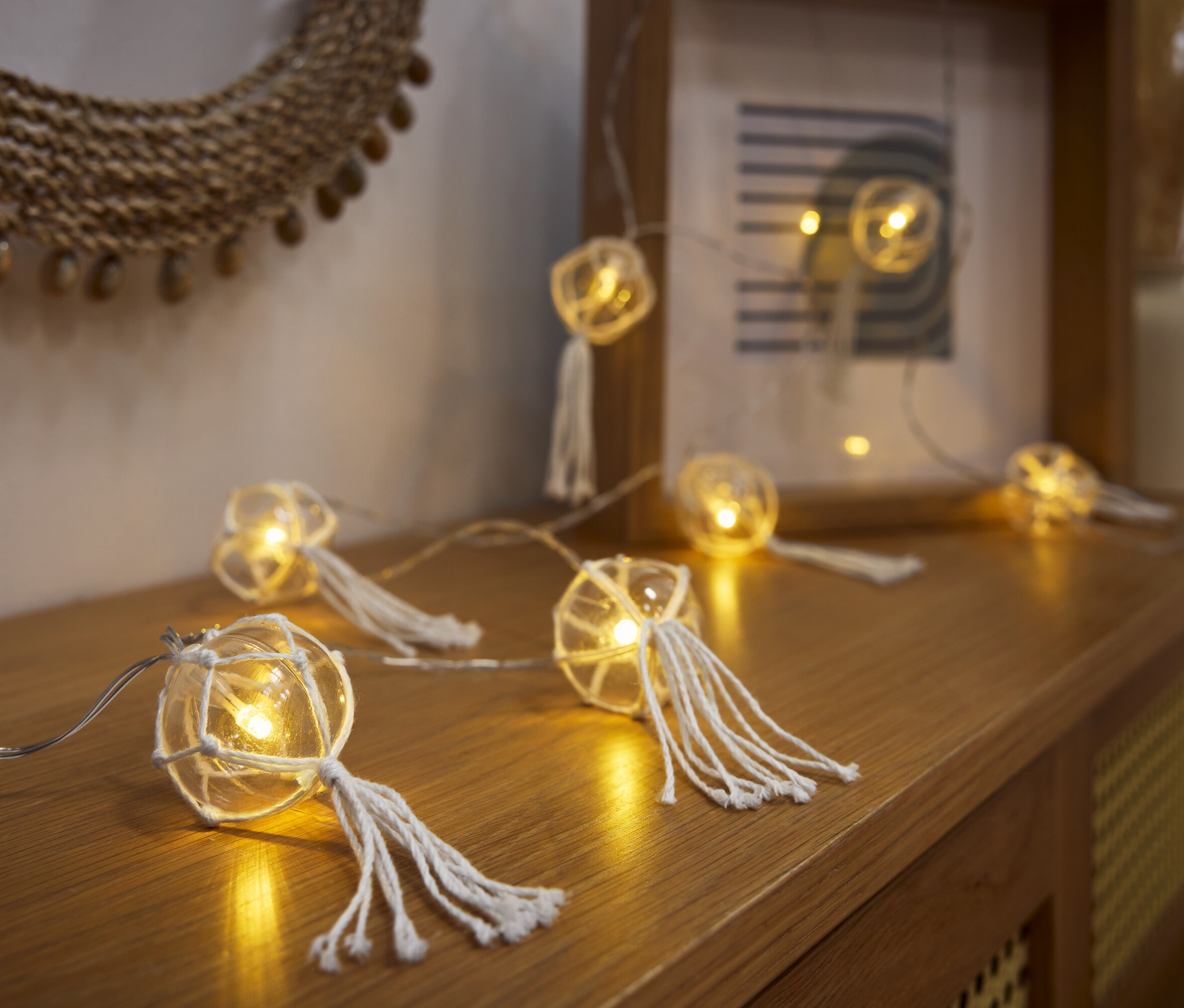 Guirlande lumineuse à LED avec des boules posée sur une commode en bois.