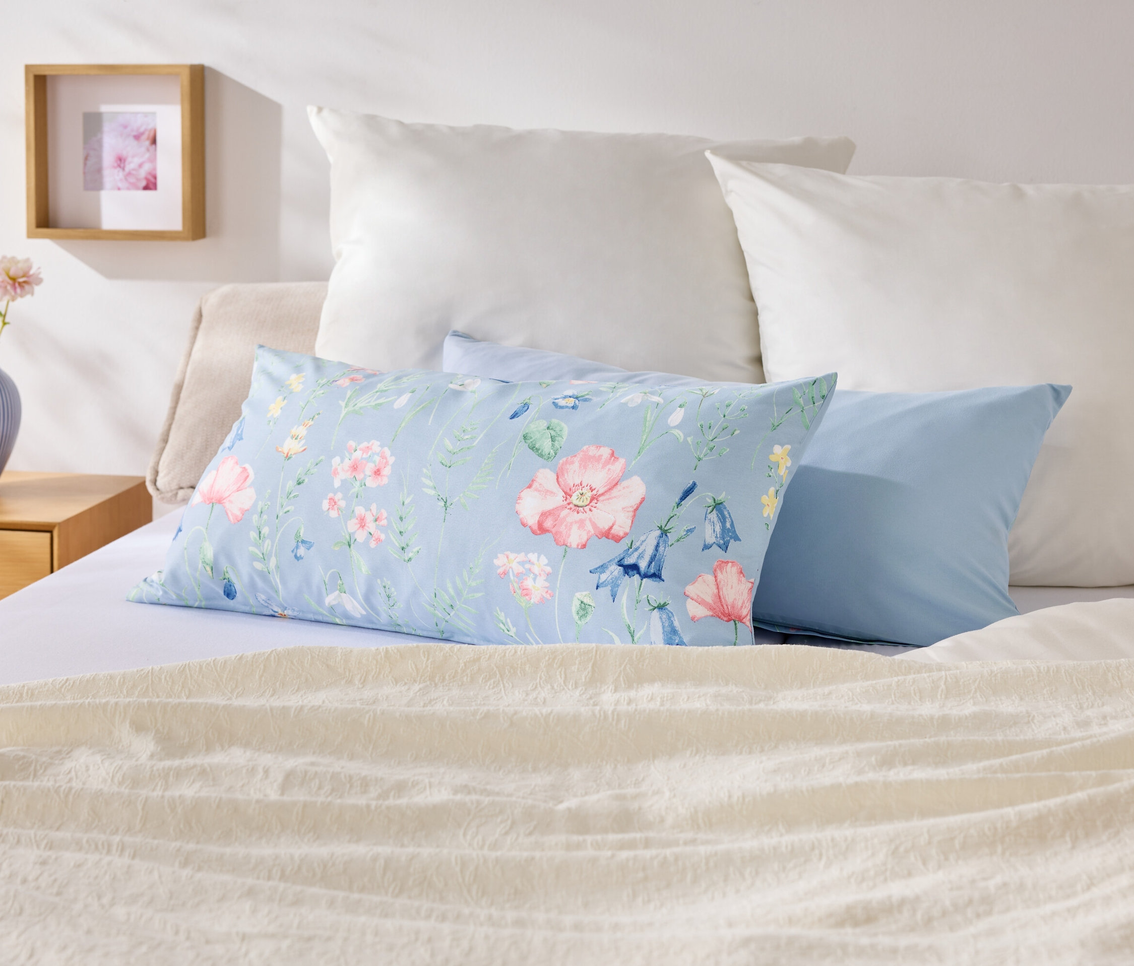 Sur un lit, des oreillers de différentes couleurs et motifs.