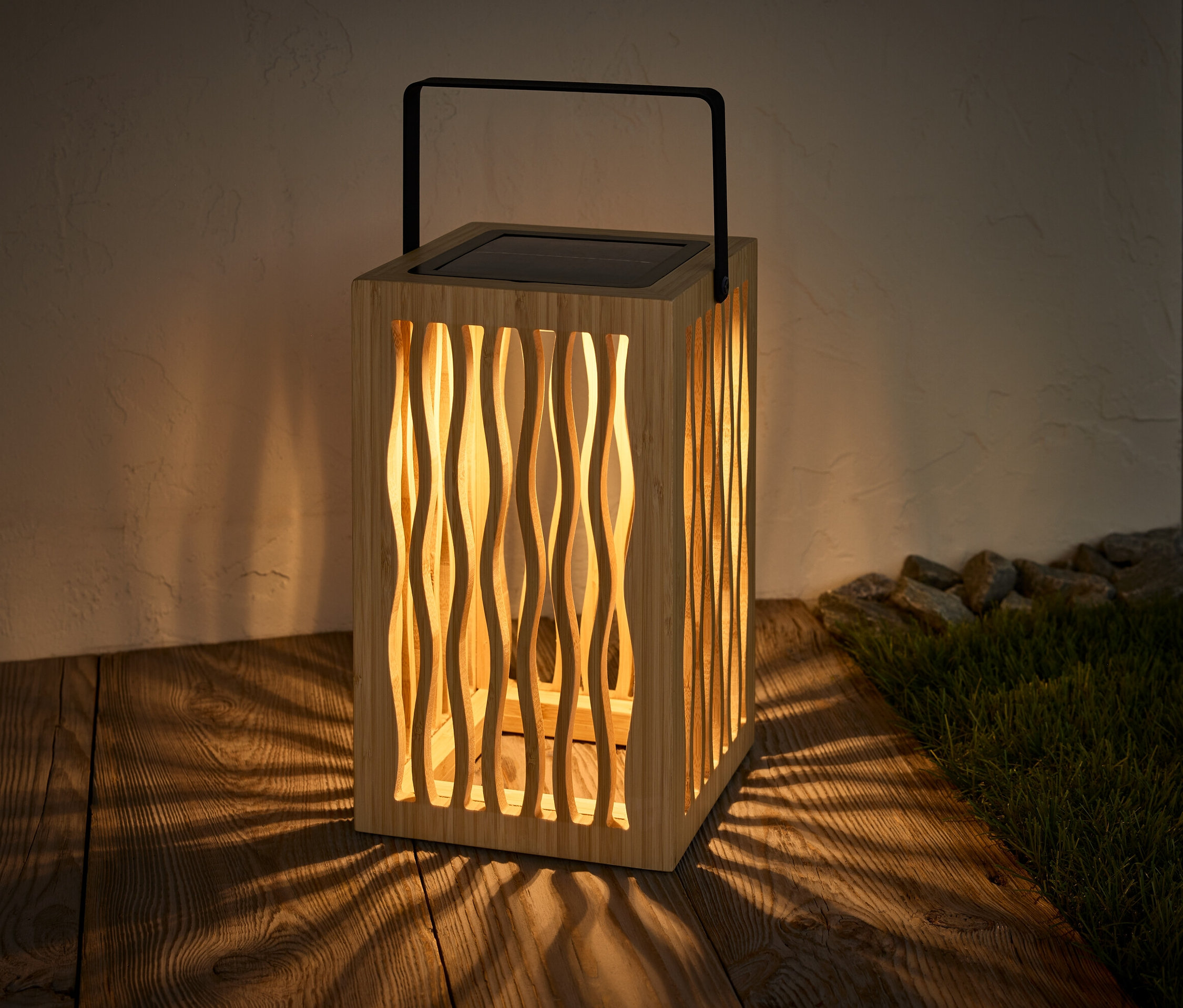 Une lanterne solaire est posée sur un plancher en bois et projette une ombre.