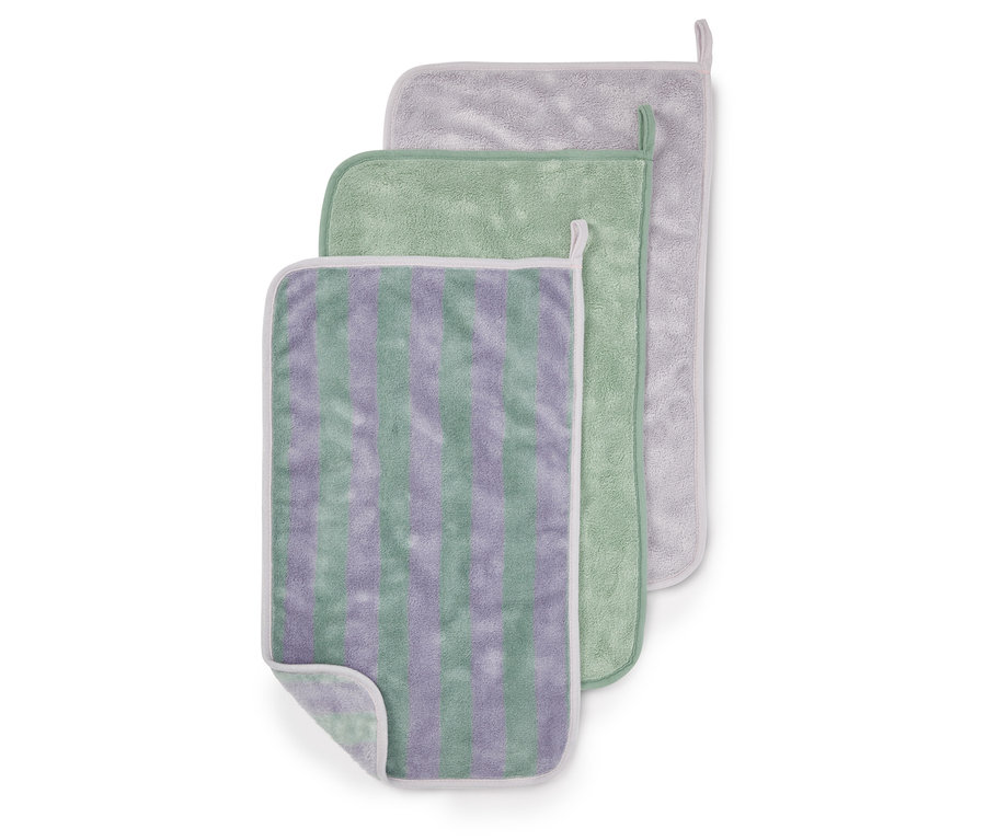 Trois débarbouillettes superposées : à rayures violettes et vertes, verte et grise avec une bordure blanche.