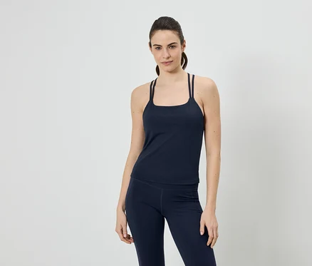 Femme portant un débardeur de sport bleu marine à bretelles et un legging sur fond neutre.