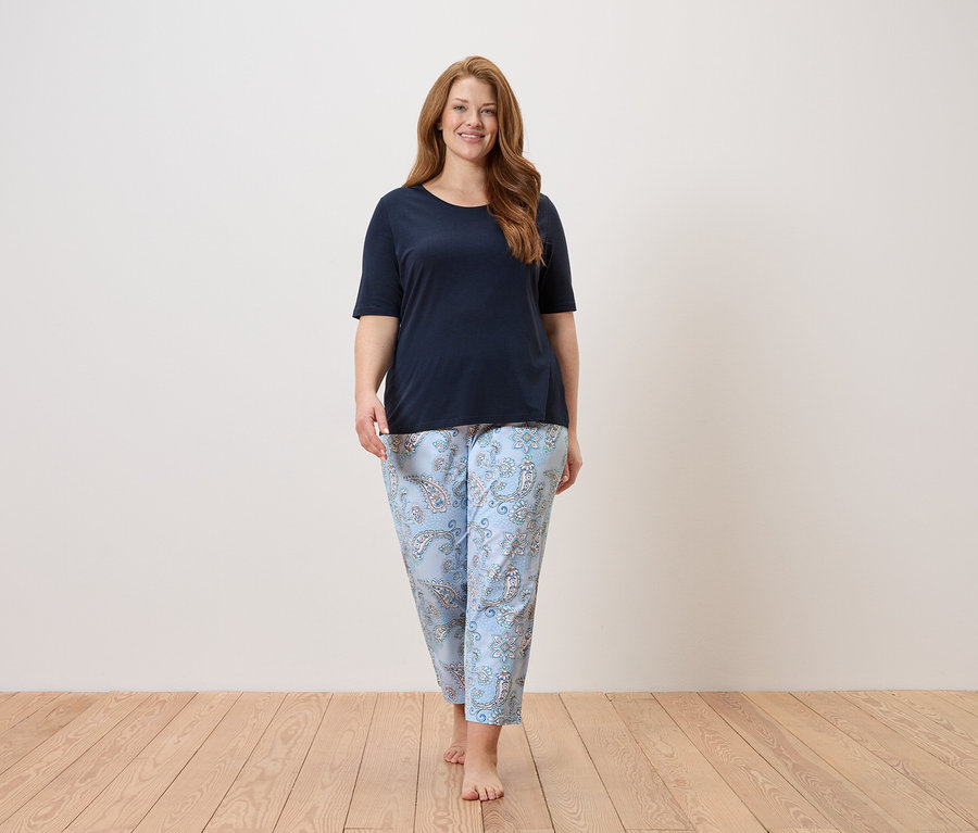 Femme marchant pieds nus dans un haut bleu marine et un pantalon bleu clair à motifs cachemire.