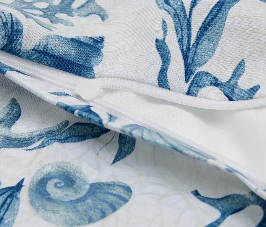 Gros plan d'un coussin blanc partiellement ouvert avec un motif marin bleu et une fermeture éclair.