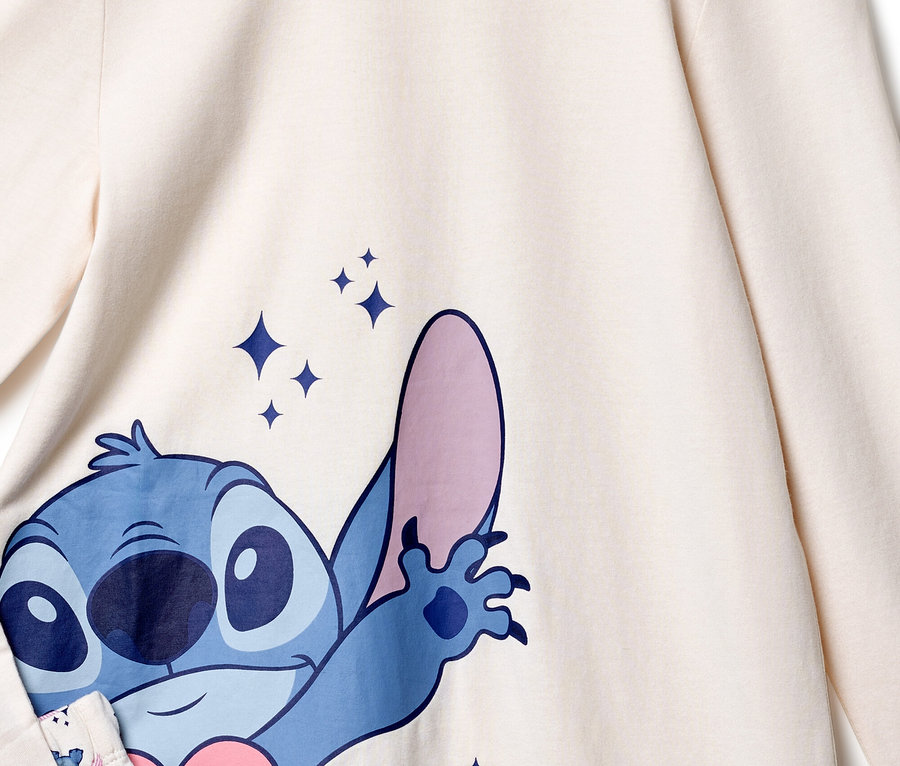 Gros plan sur un haut crème avec un imprimé bleu de Stitch et des étoiles scintillantes.