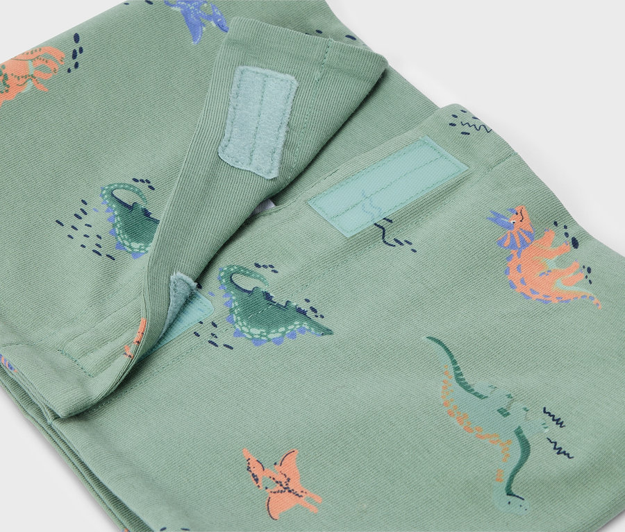 Gros plan d'un pantalon vert clair avec motif dinosaure et fermeture velcro.