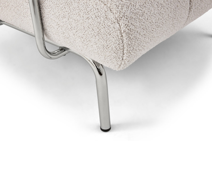 Gros plan d'un fauteuil beige avec des pieds en métal chromé sur un fond blanc.