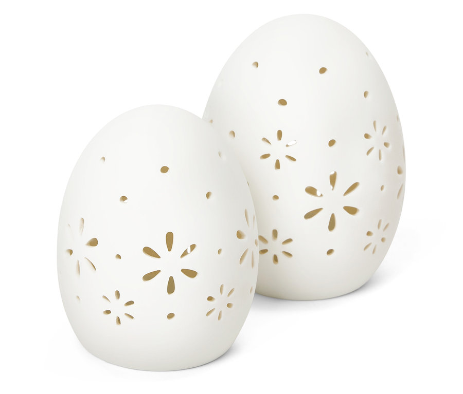 Deux œufs décoratifs blancs avec des motifs floraux découpés se tiennent sur un fond blanc.