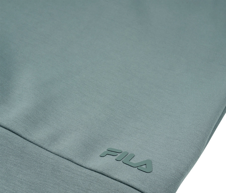 Gros plan d'un vêtement bleu-vert clair avec le logo FILA.