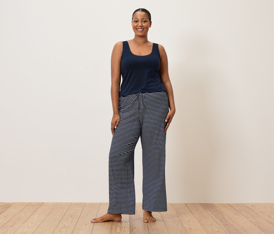 Femme portant une chemisette bleue et un pantalon rayé.