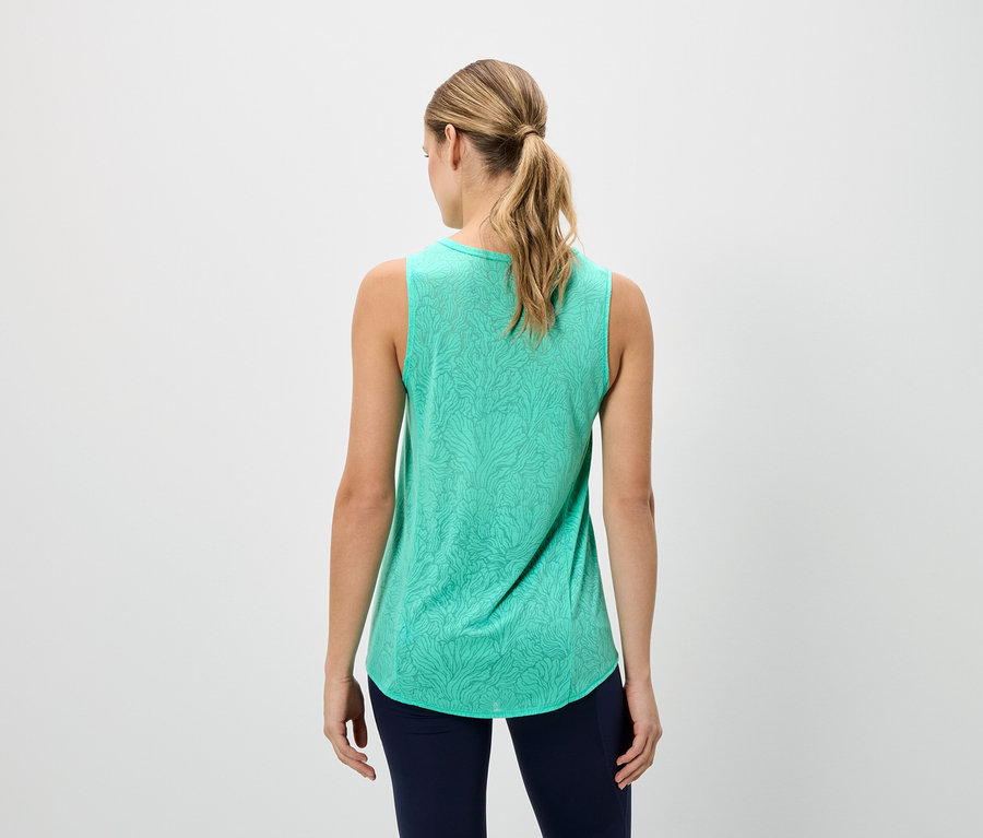 Vue arrière d'une femme blonde portant un débardeur vert sans manches à motifs et un legging bleu marine.