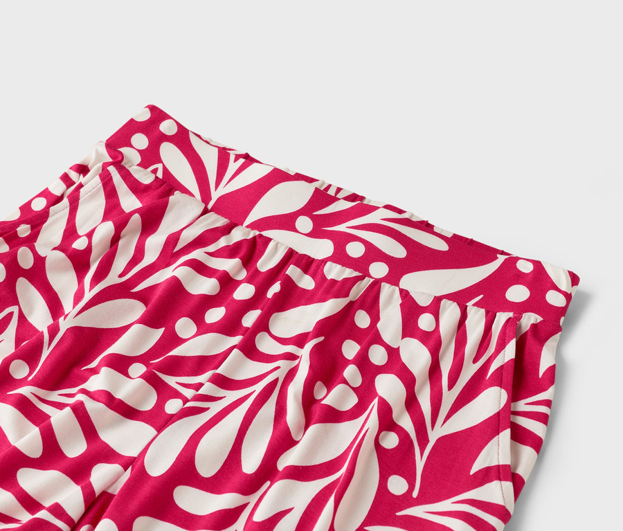 Gros plan sur un pantalon rose avec un motif de feuilles blanches.