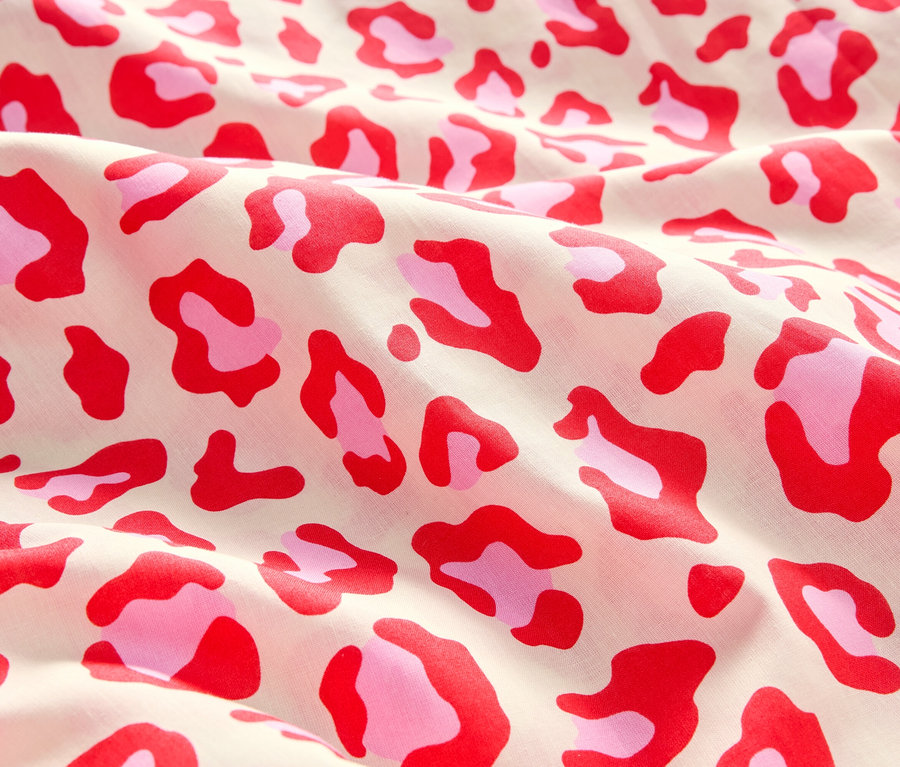 Gros plan d'un tissu avec un motif léopard rose et rouge.