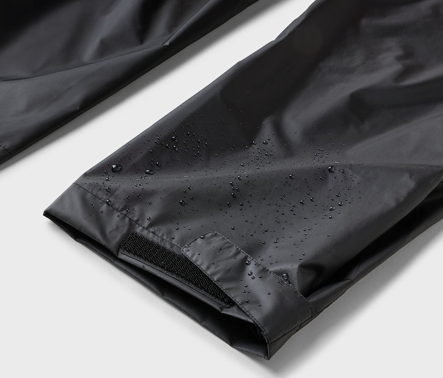 Gros plan sur un pantalon noir imperméable avec fermeture velcro.