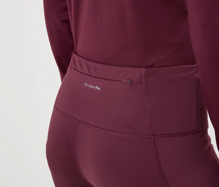 Gros plan d'une femme portant des leggings bordeaux et un haut à manches longues avec l'inscription « Dry Active Plus ».