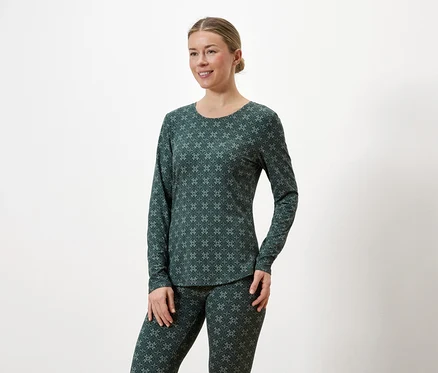 Femme portant un haut à manches longues et un legging vert foncé à motifs sur fond blanc.
