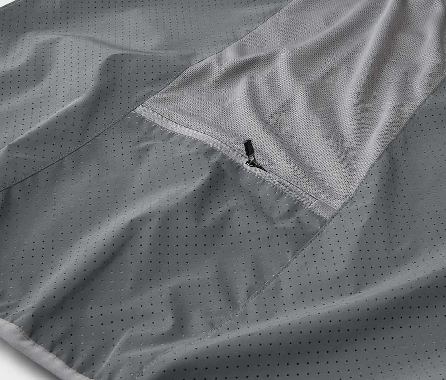 Gros plan d'une veste grise avec une poche zippée et un empiècement en maille respirante.