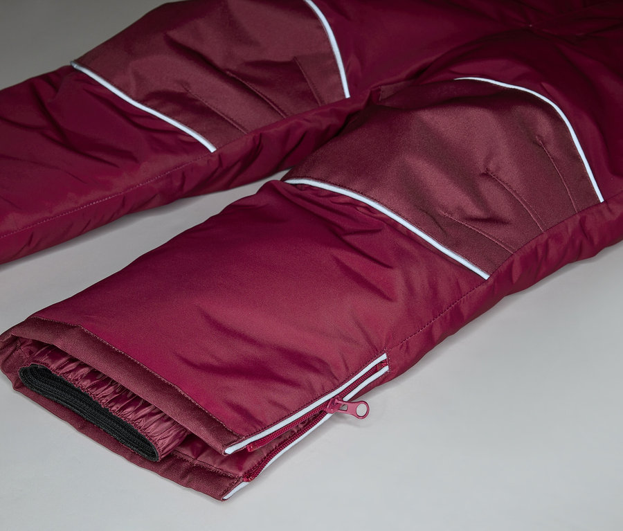 Gros plan d'un pantalon bordeaux avec des accents blancs et une fermeture éclair sur la jambe.