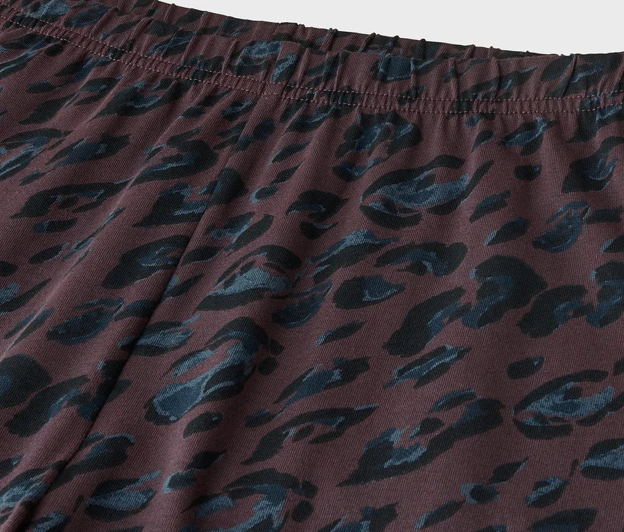 Gros plan d'un tissu marron foncé avec un motif animalier bleu foncé, montrant une ceinture élastique en haut.