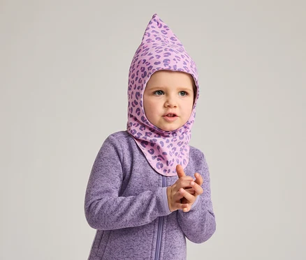 Un jeune enfant porte une combinaison violette et une cagoule violette à motif léopard.