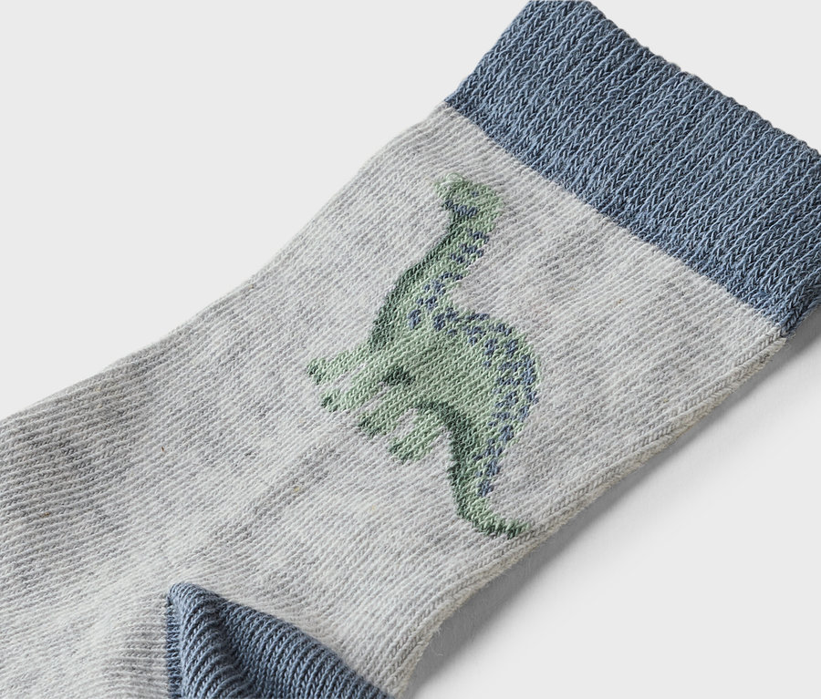 Gros plan d'une chaussette grise avec une bordure bleue et un motif de dinosaure vert.