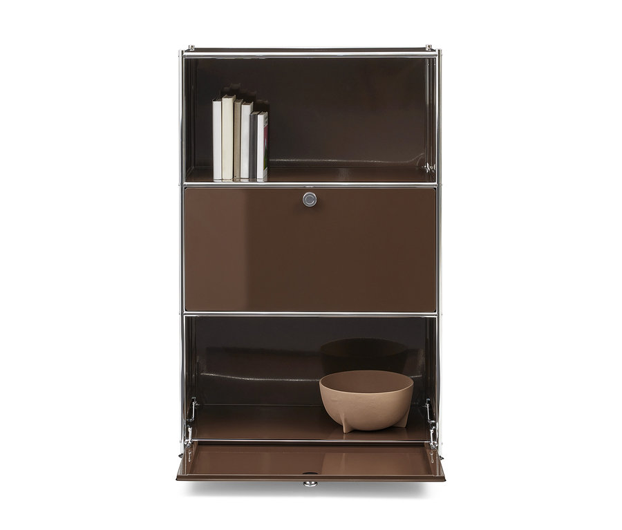 Meuble modulaire marron avec des accents chromés. L'étagère supérieure contient des livres, la section centrale est une porte fermée avec une serrure, et la section inférieure a une porte ouverte révélant un bol marron clair.